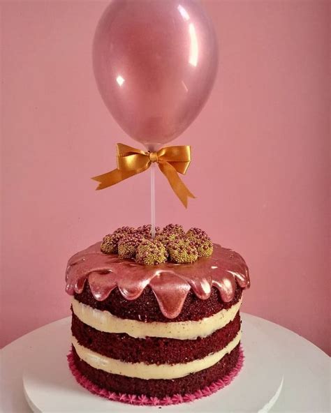 a chocolate cake with pink frosting and a balloon on top