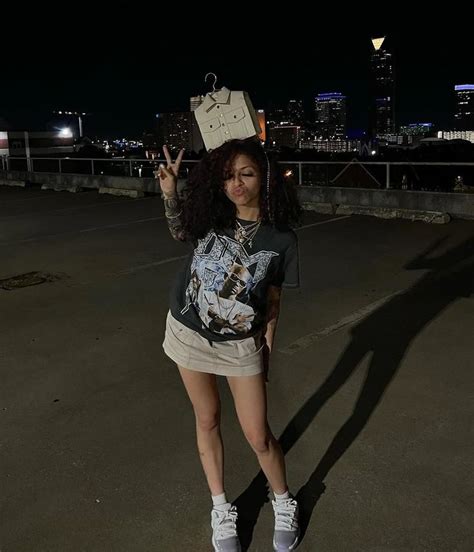 a woman standing in an empty parking lot with her hand up to the sky and wearing a crown