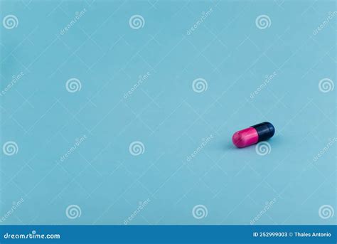 A Pink and Black Pill on a Light Blue Surface Stock Image - Image of treatment, cure: 252999003