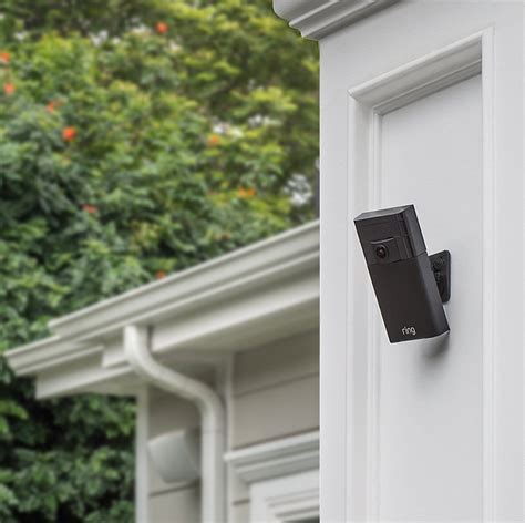 an open door with a security camera attached to the side of it and trees in the background