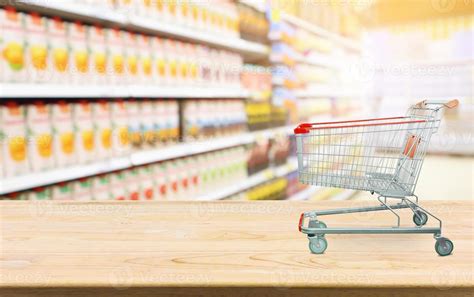 Supermarket with product shelves blur background with empty shopping cart on wood table 12580182 ...