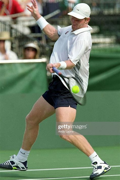 a man swinging a tennis racquet at a ball on a court with people watching