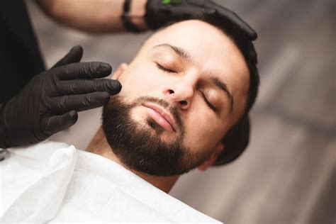 Afeitarse la barba en una barbería con una navaja de afeitar peligrosa. | Foto Premium