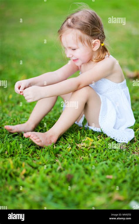 Adorable little girl sitting on a grass Stock Photo - Alamy