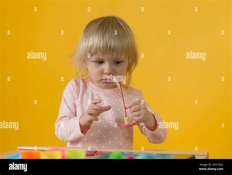 A girl in pink pajamas against a yellow wall enthusiastically plays a ...