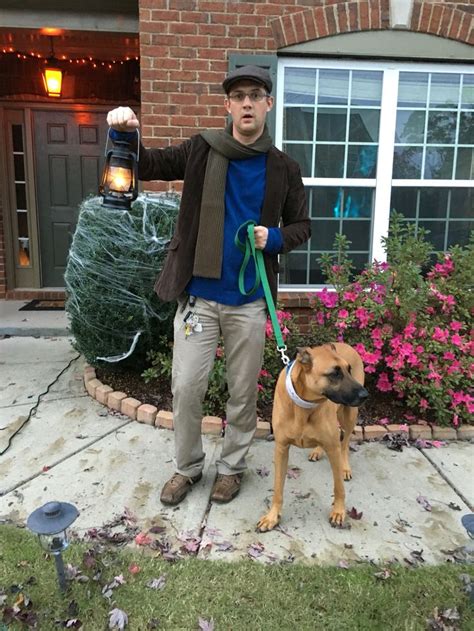 a man holding a dog on a leash in front of a house