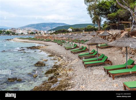 Rows of sun loungers under straw umbrellas on an empty beach in cloudy ...