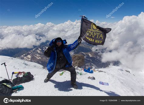 2014 07 Mount Elbrus, Russia: Man holding the flag of Sparta on top of ...