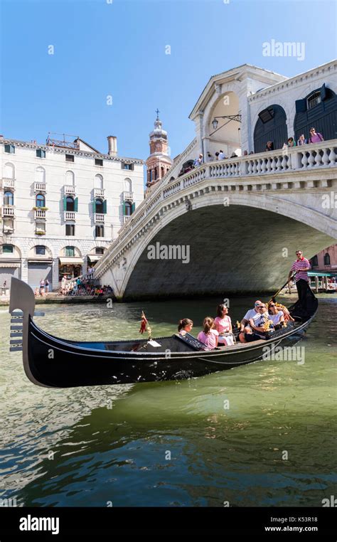 A gondola rides under the Rialto Bridge, Italy Stock Photo - Alamy