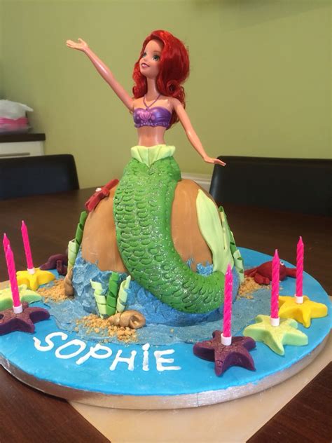 there is a cake with a mermaid on it and candles in the shape of a ballon