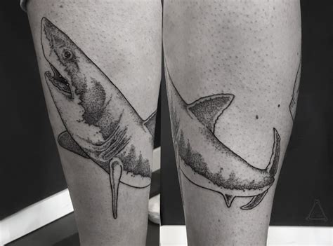 two black and white tattoos of sharks on the legs, one with a large shark in it's mouth