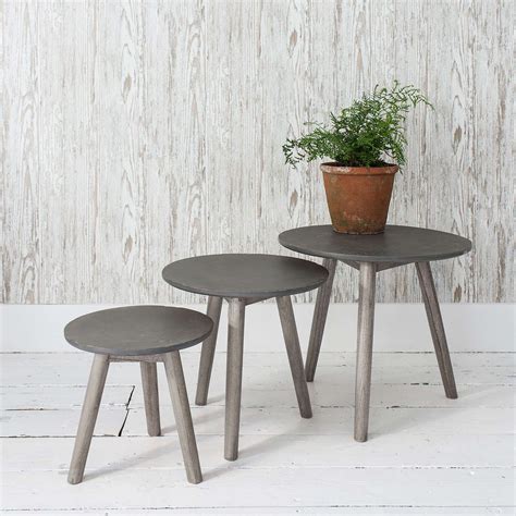 two small tables with plants on them in front of a white wooden wall and floor