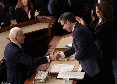 Speaker Mike Johnson shakes his head and grimaces next to Kamala