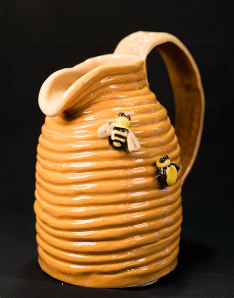a ceramic vase with two bees on it's front and side, against a black background