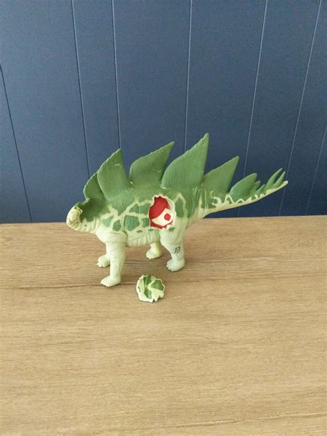 a green toy dinosaur on a wooden table