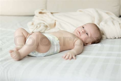 Cute baby boy in diapers lying on bed | Stock image | Colourbox