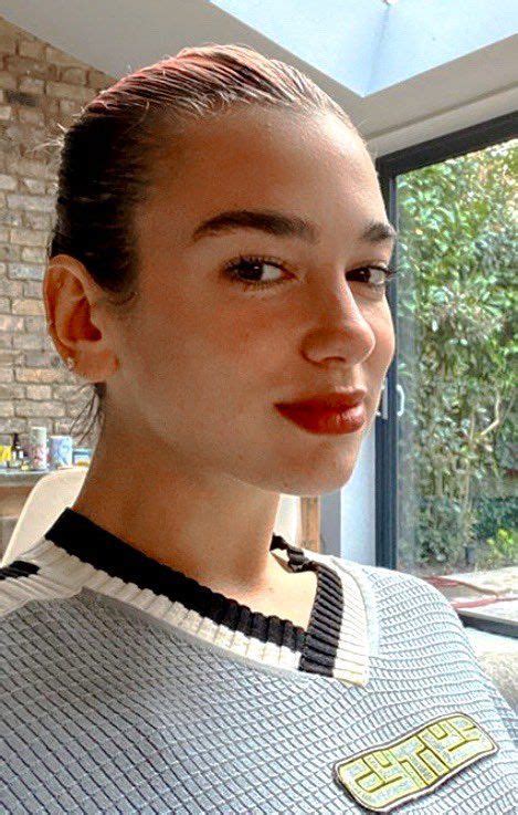 a woman with red lipstick standing in front of a brick wall and looking ...