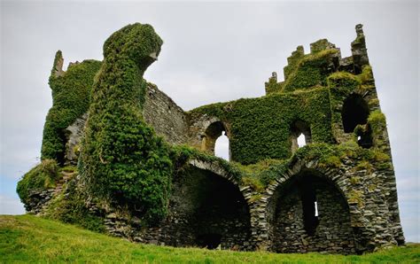 an old stone building with ivy growing on it's sides and windows in the middle