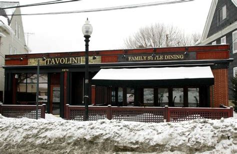 a restaurant with snow on the ground in front of it and street lights next to it