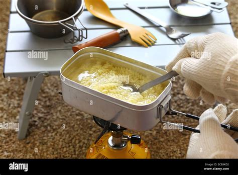 camping cooking. boiling pasta in mess tin Stock Photo - Alamy