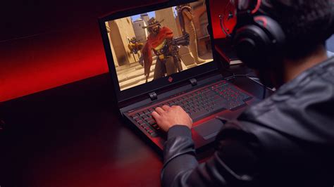 a man wearing headphones and using a laptop computer on a gaming desk with red lighting