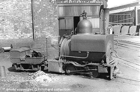 black and white photograph of an old steam engine parked in front of a brick building