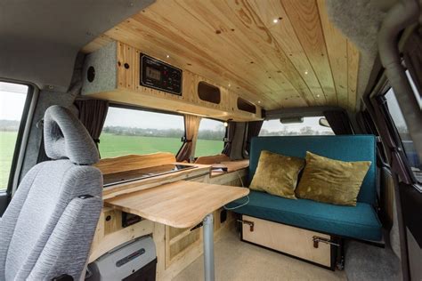 an interior view of a camper van with wood paneling and blue couches