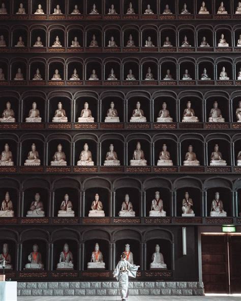 a man standing in front of a wall full of statues