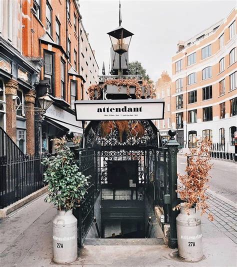 the entrance to an outdoor cafe with potted plants on the sidewalk and ...