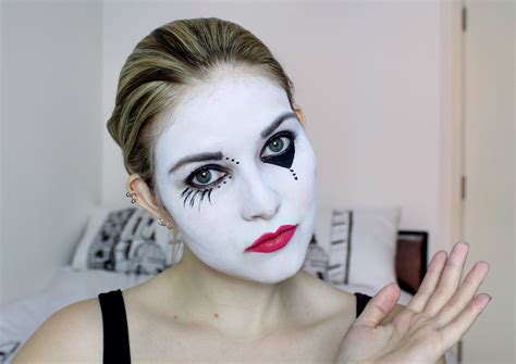 a woman with white makeup and black make up holding her hand in front ...