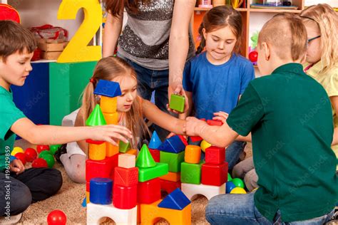 Children building blocks in kindergarten. Group kids playing toy on floor. Top view of interior ...