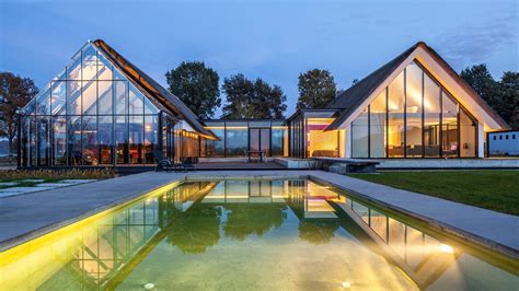 A gabled greenhouse appears to slide out from beneath the thatched roof of this villa, completed ...