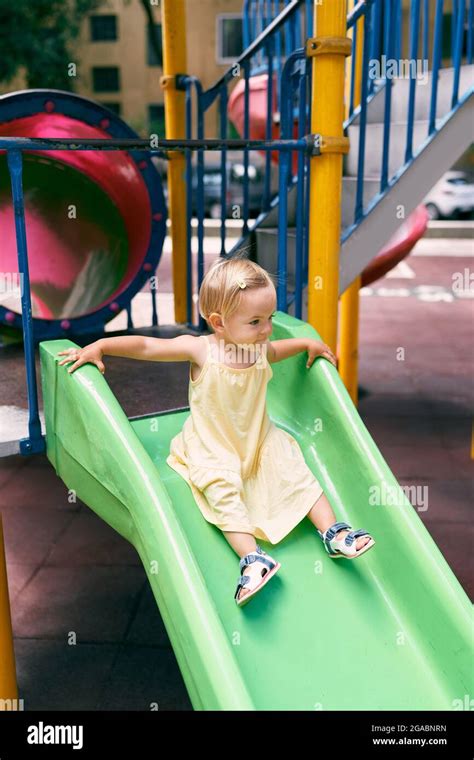 Little girl in a dress slides down a slide on the playground Stock Photo - Alamy