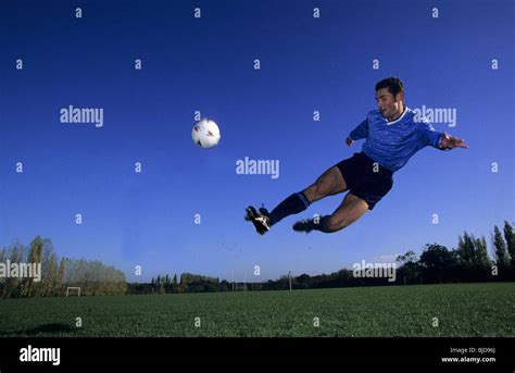 Soccer player kicking the ball mid-air Stock Photo - Alamy