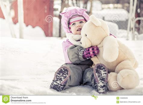 Beautiful Baby Embracing Toy Plush Bear Sitting on Snow in Park in Cold ...