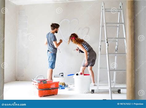 Young Couple Painting Walls in Their New House. Stock Photo - Image of painting, home: 98767652