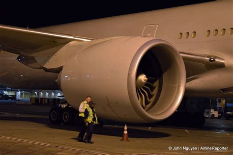 Ground crew stand next to a American Airlines 777-300ER’s huge GE90 ...