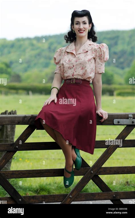 Woman in old fashioned clothing sitting on gate Stock Photo - Alamy