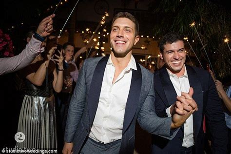 two men dancing at a party with people holding sparklers in the air behind them