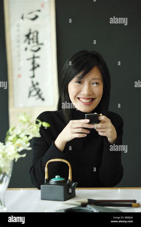 Young woman drinking Chinese tea, smiling at camera Stock Photo - Alamy