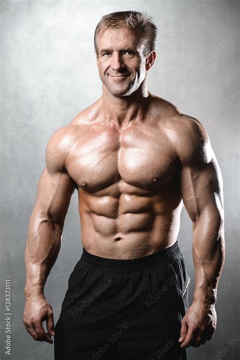 Brutal strong bodybuilder old man posing in studio grey background ...