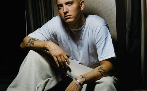 a man sitting on the floor with his arms crossed and tattoos on his arm, looking at the camera