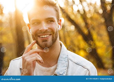 Image of Handsome Young Caucasian Man Using Earbuds while Walking in Park Stock Image - Image of ...