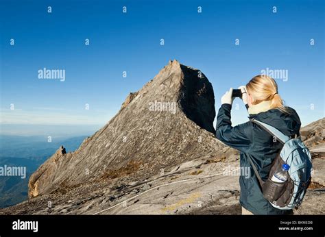 A climber photographs the scenery at the summit of Mt Kinabalu. Kinabalu National Park, Sabah ...