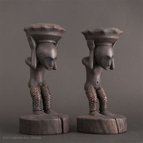 two statues are standing next to each other, one is carrying a bowl on his head