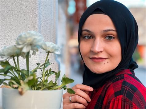 Premium Photo | A woman wearing a hijab stands next to a potted plant