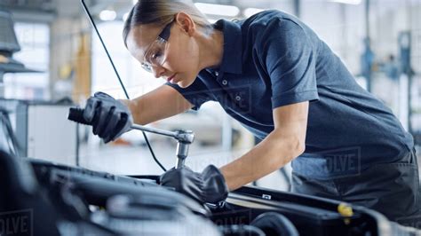 Beautiful Empowering Female Mechanic is Working on a Car in a Car Service. Woman in Safety ...