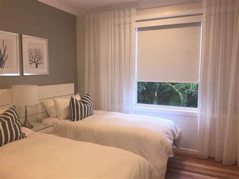 White Blockout Roller blinds and matching pelmet with White sheer S wave curtains to soften the ...