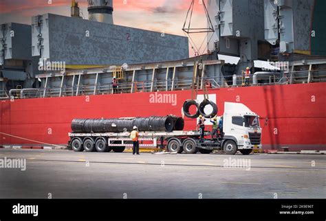 Cargo ship discharging steel wire rod at port terminal. Truck load ...