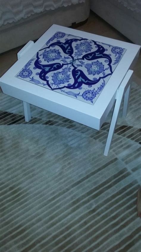 a white coffee table with blue and white tiles on the top, sitting in front of a couch